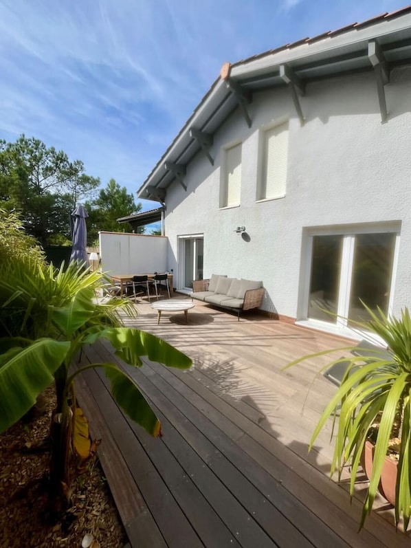 A house with a deck, a sofa, and a dining table.