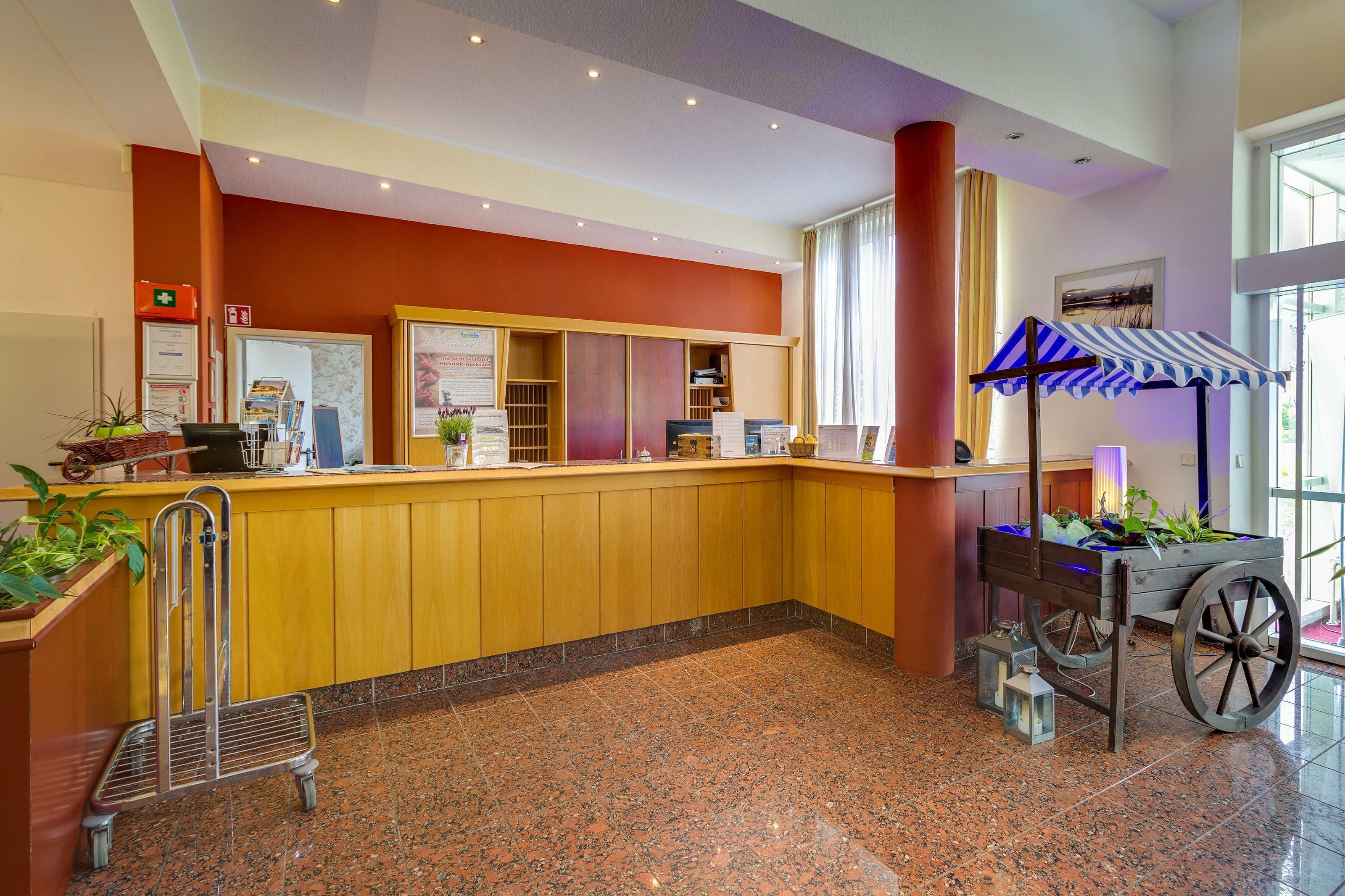 A reception area with a wooden counter, a blue-striped umbrella, and a plant cart.