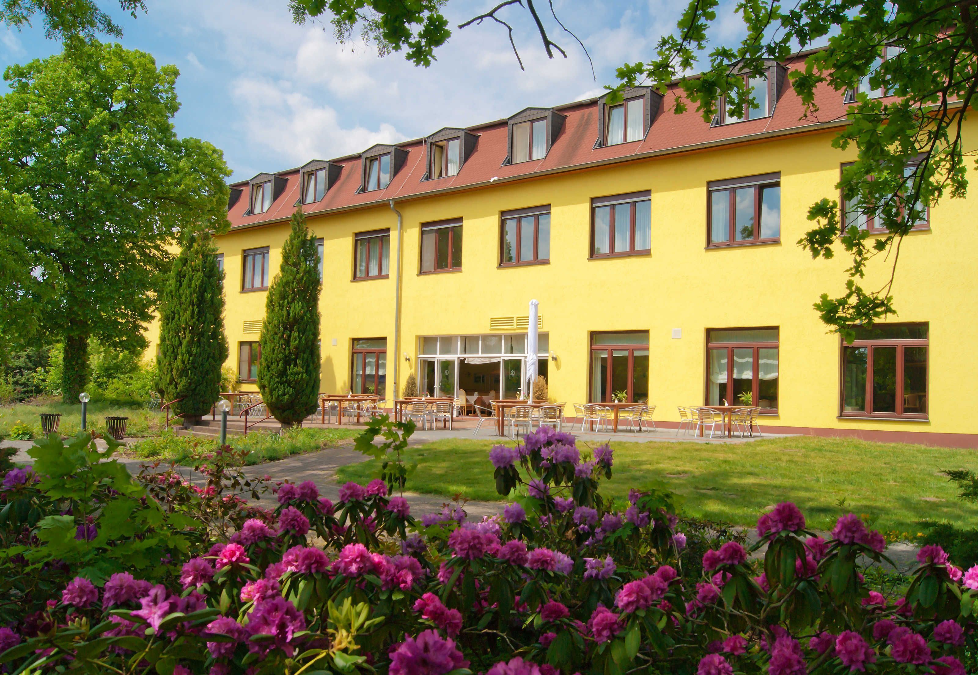 A yellow building with multiple windows and a covered outdoor seating area.