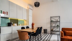 A modern kitchen with white cabinets, a wooden dining table, black chairs, and a black and white patterned floor. - Ruby Orange Apartment, WiFi, AC !New! (Lisboa)