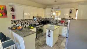 Una cocina amplia con armarios blancos, encimera de granito, horno integrado y refrigerador.
