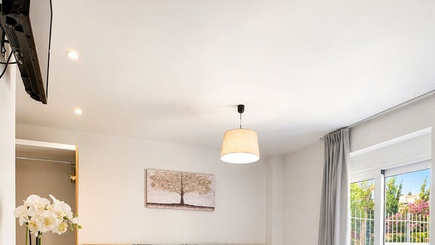 A modern hotel room with a bed, a desk, a chair, a TV, and a painting on the wall. - Deluxe City (Chania)