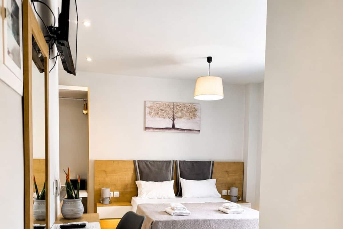 Una habitación de hotel moderna con cama, mesitas de noche, un escritorio, una silla, una lámpara y un cuadro en la pared.