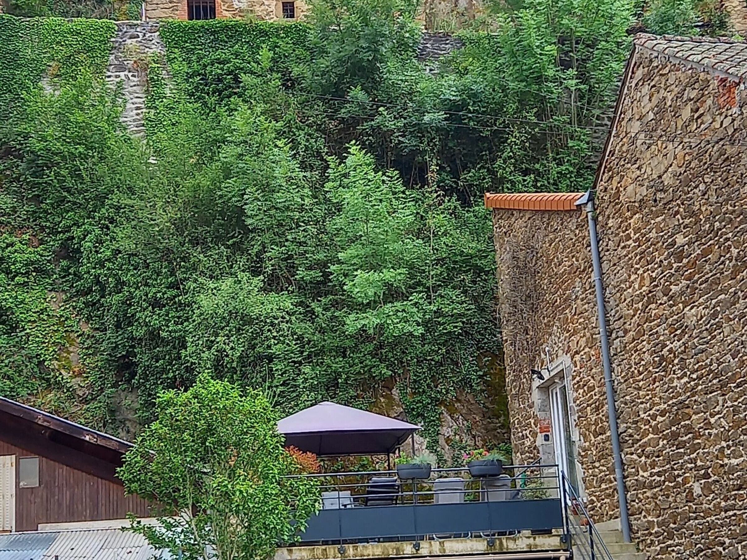 A stone building with a balcony overlooking a lush green hillside.