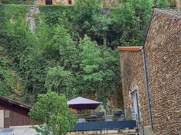 A stone building with a balcony overlooking a lush green hillside.