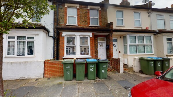A row of terraced houses with green recycling bins in front.