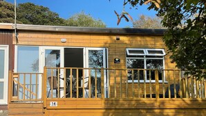 Una cabaña de madera con balcón, ventanas grandes y un letrero que indica que se encuentra en un parque.