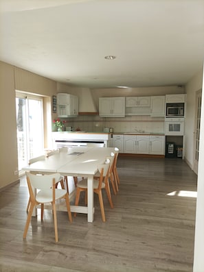 A spacious kitchen with white cabinets, a central island, and a dining area with wooden chairs.