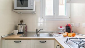 A modern kitchen with a microwave, sink, and gas stove. - HouSmart Vicolo Bolognetti (Bologna)