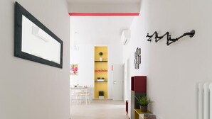 A hallway with a framed picture, a red accent on the ceiling, a plant on a shelf, and a radiator on the wall. - HouSmart Vicolo Bolognetti (Bologna)