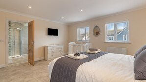 Une chambre à coucher avec un lit, une commode, un téléviseur et une fenêtre.