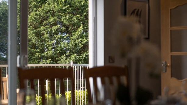 Un espace repas offrant une vue sur une forêt verdoyante grâce à une porte vitrée.