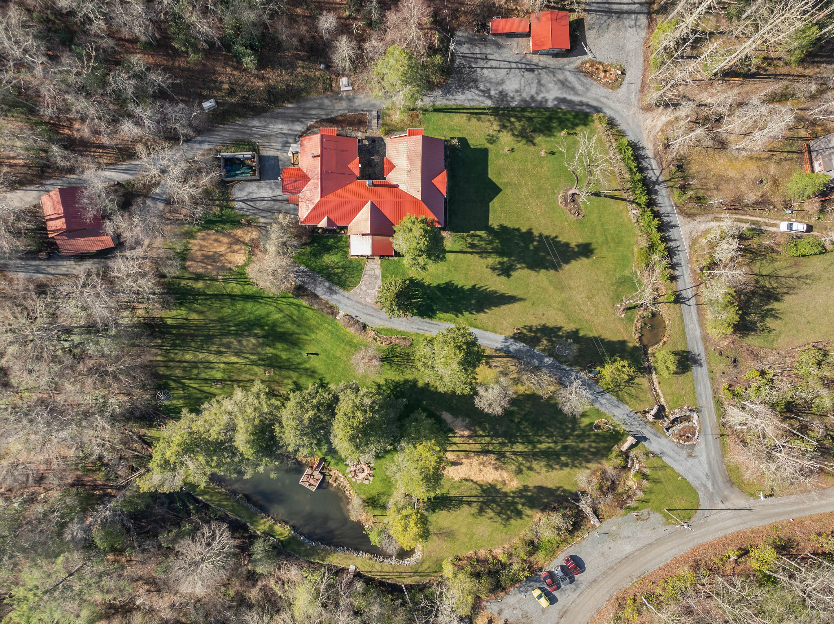 An aerial view of a property with multiple buildings, a winding road, and a river.