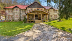 A log cabin with a stone pathway leading to the entrance, surrounded by a well-maintained lawn and trees. - Glen Choga Lodge (Topton)