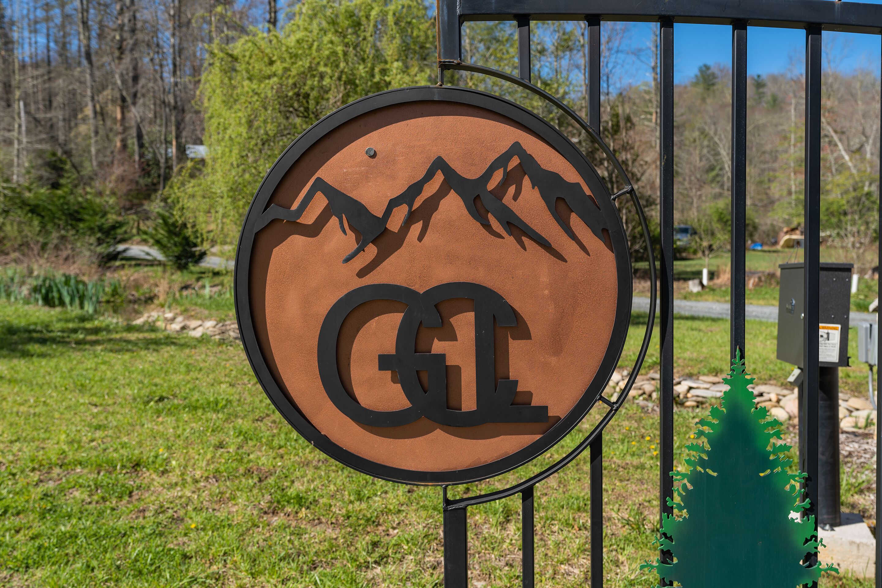 Un panneau circulaire représentant la silhouette d’une montagne, avec les lettres « GE » au centre, fixé sur un poteau métallique.