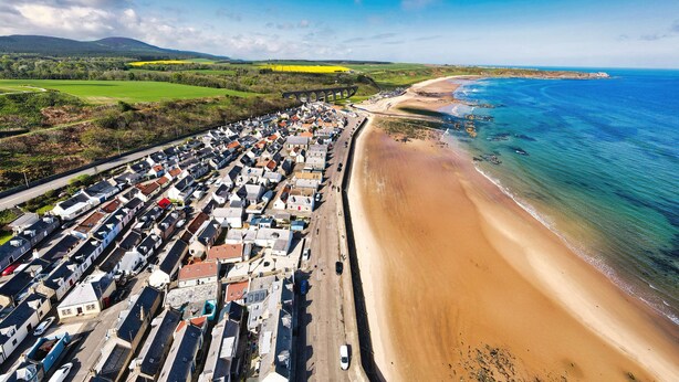 A coastal town with a long beach, a bridge, and a dense cluster of buildings. - Eider Cottage (Buckie)
