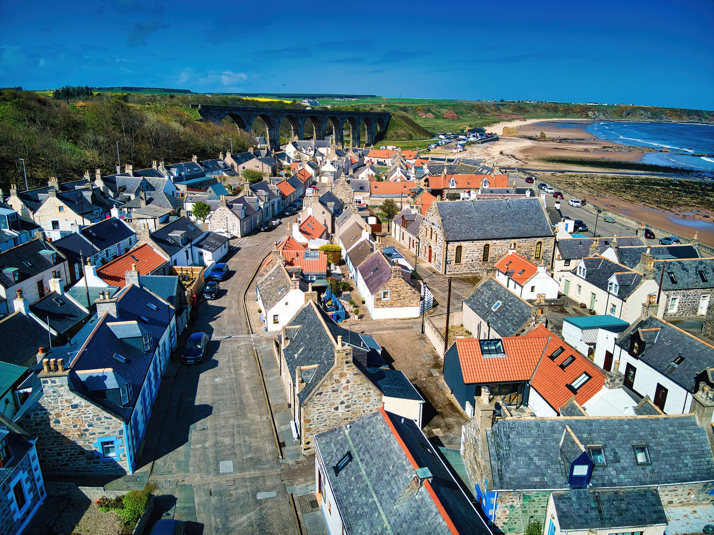 A coastal town with stone buildings, a bridge, and a beach.