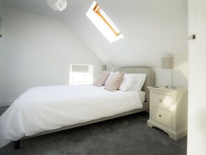 A bedroom with a bed, a nightstand, a lamp, and a window with a view.