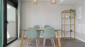 Un área de comedor con una mesa de vidrio, cuatro sillas y dos lámparas colgantes.