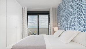 Una habitación de hotel moderna con una cama grande, vista al cielo a través de un ventanal y una pared con diseño.