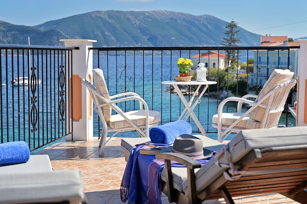 Un balcon avec deux fauteuils en osier blanc, une petite table ronde ornée d’une plante et une serviette bleue.