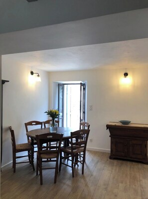 A dining area with a wooden table and chairs, a vase with flowers, and a wooden cabinet. - Family home in the heart of the village of Nonza (Nonza)