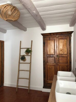 Une pièce avec une porte en bois, un lavabo blanc et une échelle en bois sur laquelle sont posées des plantes en pot.