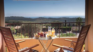 Un balcon avec une table dressée pour le petit-déjeuner, offrant une vue sur un paysage magnifique.
