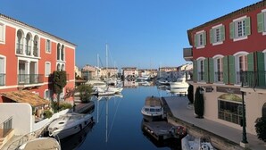Uma marina com barcos atracados, edifícios com varandas e um céu limpo.