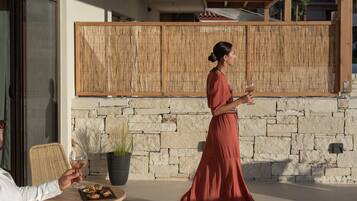A woman in a red dress walking past a table with a glass of wine and a plate of food.