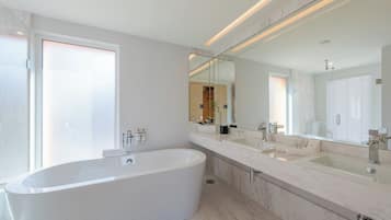 A modern bathroom with a freestanding bathtub, a large mirror, and a double sink vanity.