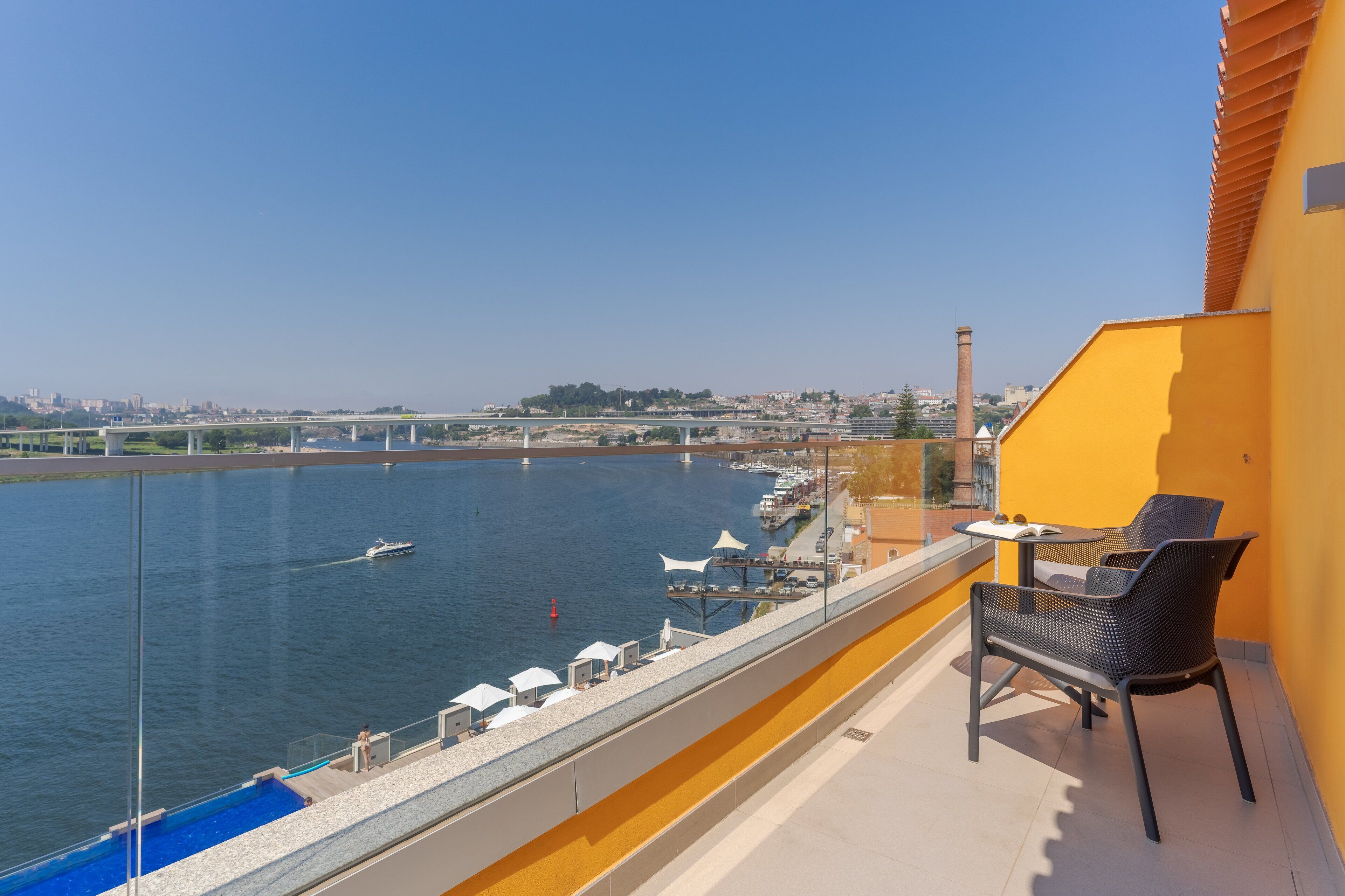 Un balcon avec vue sur une rivière, un pont et un paysage urbain en arrière-plan.