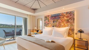 A modern hotel room with a large bed, a desk with a laptop, a chair, and a view of a body of water. - Pestana Douro Riverside - Preferred Hotels & Resorts, Lifestyle (Gondomar)