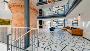 A spacious lobby with a geometric patterned floor, a brick column, a staircase, and a modern chandelier. - Pestana Douro Riverside - Preferred Hotels & Resorts, Lifestyle (Gondomar)
