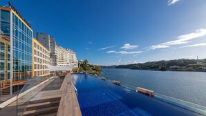 A modern hotel with a large infinity pool overlooking a body of water, a glass facade, and a clear sky. - Pestana Douro Riverside - Preferred Hotels & Resorts, Lifestyle (Gondomar)