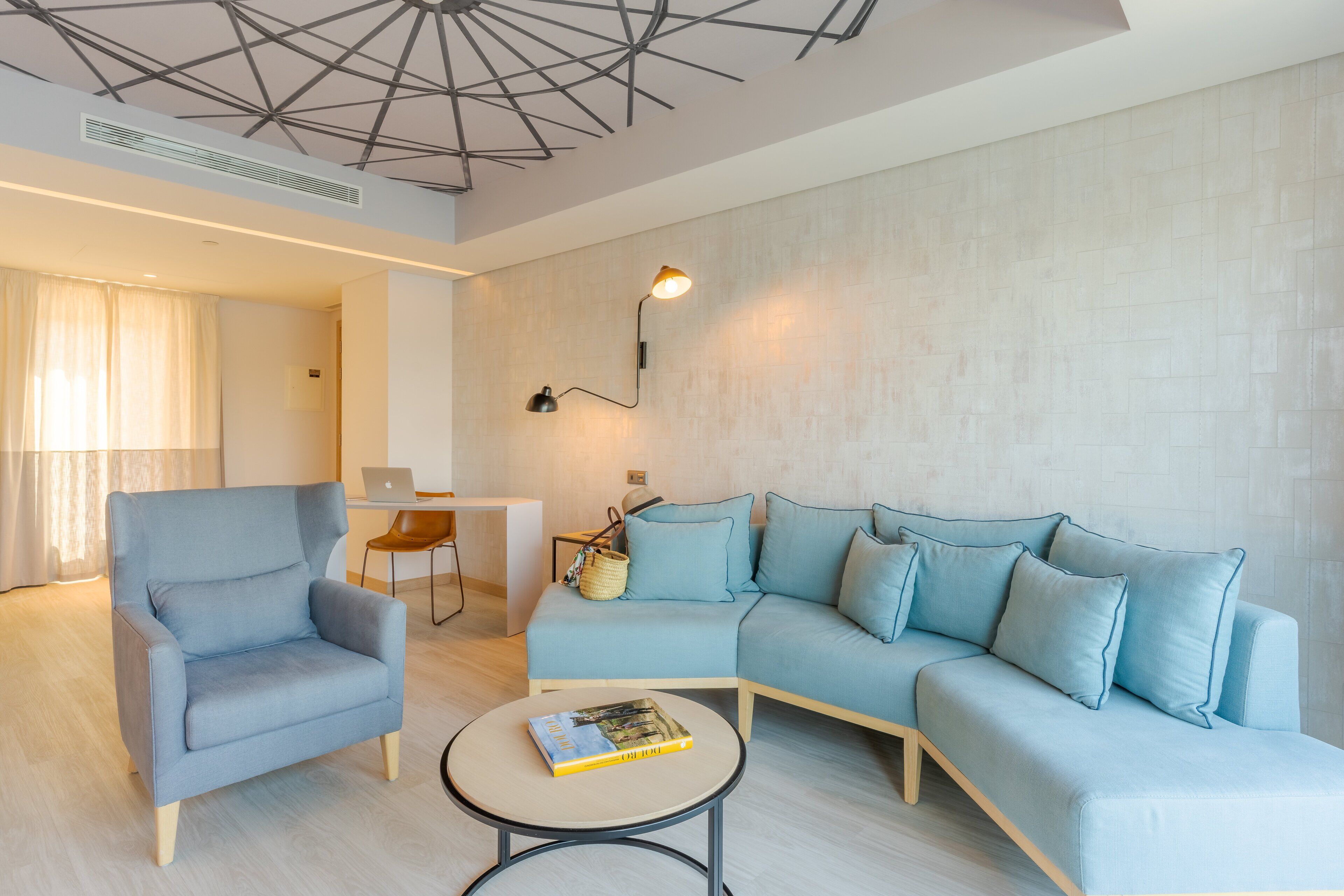 A modern living room with a light blue sofa, a matching armchair, and a small round table with a book.