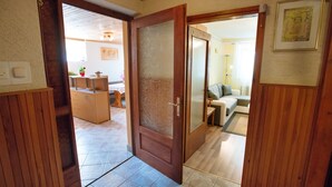A hallway with a wooden door leading to a living area. There is a small table with a plant and a chair in the living area. - Apartment Jorsi With Mountain View (Zrece)