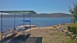A beach with a covered seating area, a table, and an umbrella.