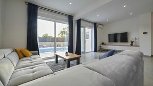 A modern living room with a sofa, a coffee table, and a TV. - Blue fantasy is new modern villa 5 min from the beach! (Kaštel Novi)