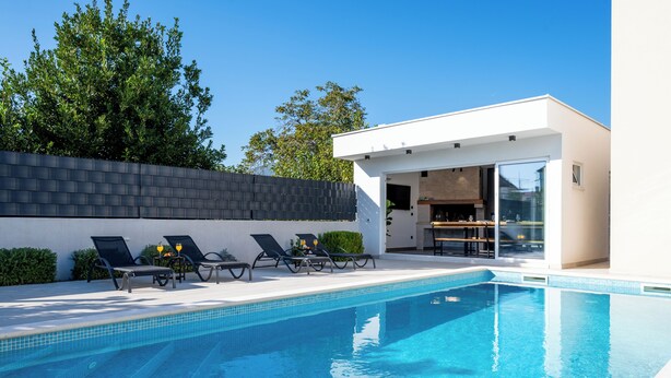 A modern outdoor pool area with lounge chairs and a clear blue pool. - Blue fantasy is new modern villa 5 min from the beach! (Kaštel Novi)