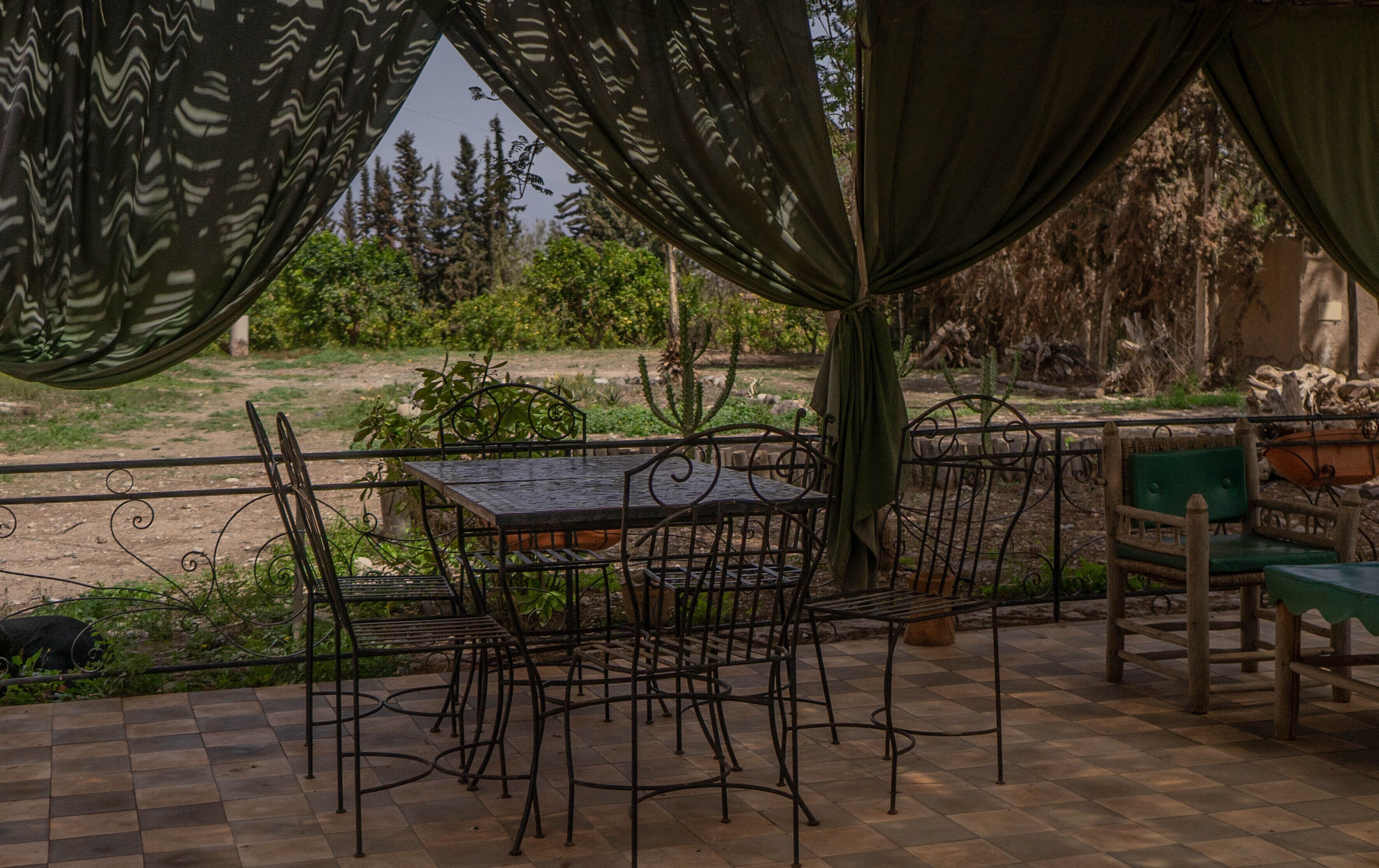 An outdoor patio with a checkered floor, metal chairs, and a table.