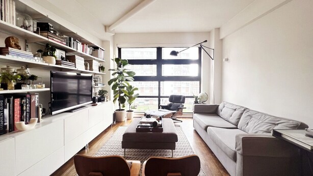 A modern living room with a flat-screen TV, a sofa, a coffee table, and a bookshelf filled with books and decorative items. - London Warehouse One Bedroom Apt (London)