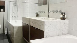 A modern bathroom with a glass-enclosed shower, a large bathtub, and a vanity with a mirror. - London Warehouse One Bedroom Apt (London)