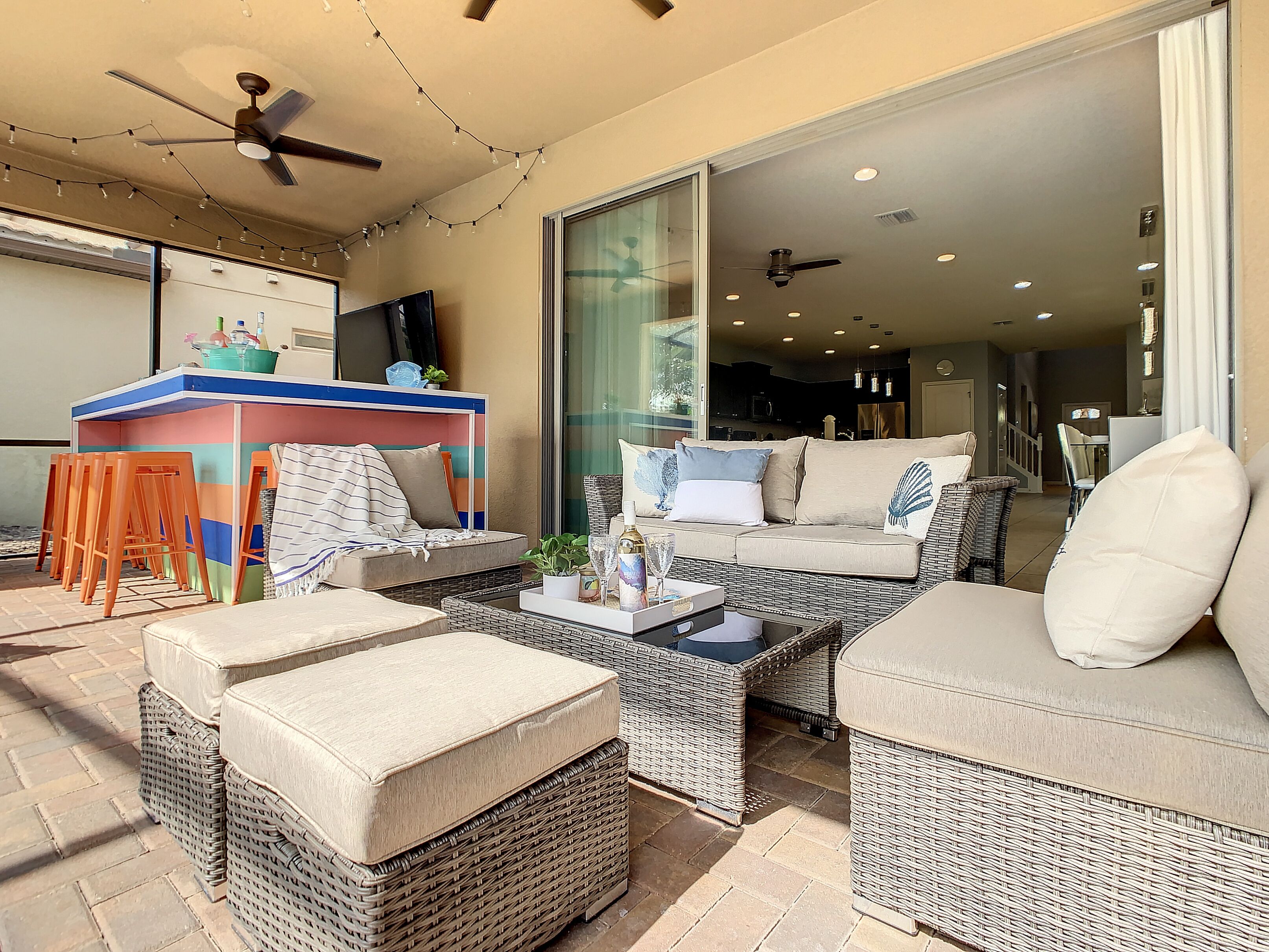 Un patio amplio con mobiliario de mimbre, una zona de bar y un ventilador de techo.