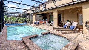 Piscina con jacuzzi, sillas de descanso y un patio cubierto.