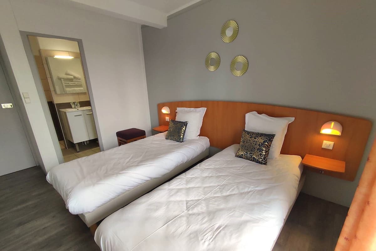 Een hotelkamer met twee bedden, een houten hoofdbord, bedlampen en een spiegel.