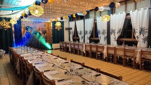 A banquet hall with long tables set for dining, decorated with balloons and string lights. - Kamea Club La Gironie (Turenne)