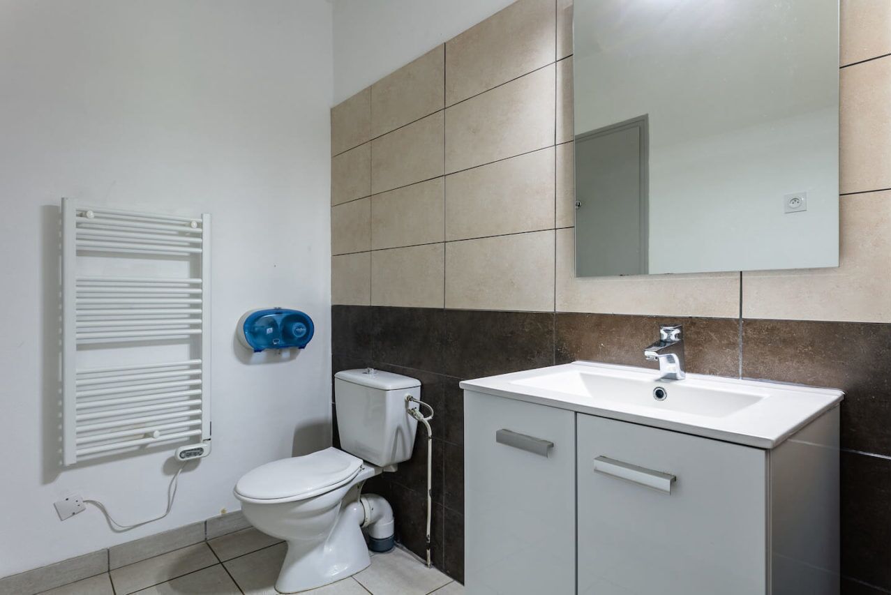 Une salle de bain moderne équipée de toilettes, d’un lavabo et d’un porte-serviettes.