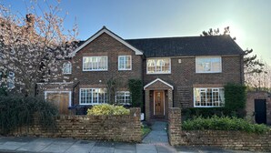 A two-story brick house with a front entrance, a driveway, and a garden.