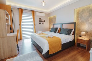A modern bedroom with a large bed, a desk, and a nightstand.